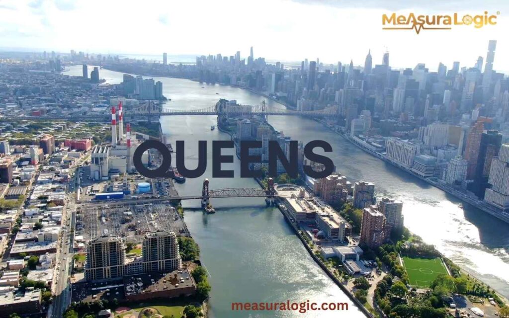 High-altitude view of Queens and the East River, featuring large industrial smokestacks and the Manhattan bridge.