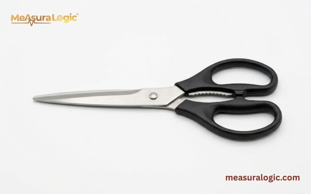 A pair of scissors with black plastic handles is centered on a white surface.