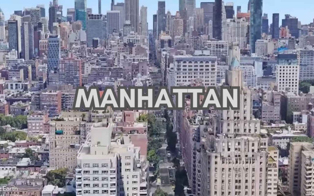 A dense, daytime aerial "canyon" view looking down a long Manhattan street flanked by countless skyscrapers.