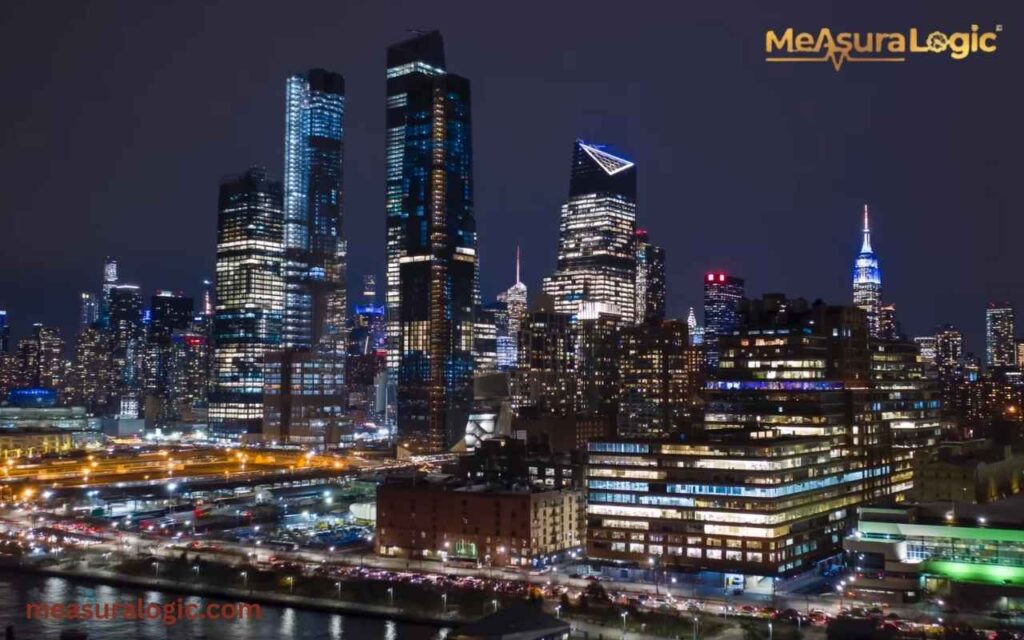 Nighttime view of illuminated New York overlooking a busy industrial area and waterfront.