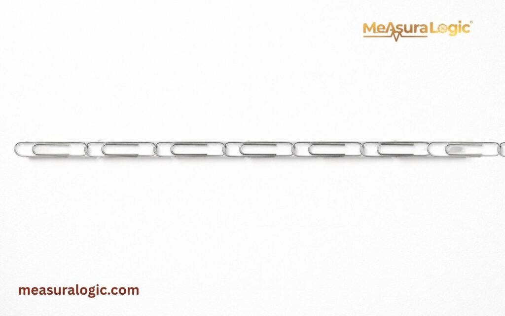 A horizontal line of silver metal paper clips linked together against a plain white background. The clips are arranged in a straight, uniform chain across the center of the frame.