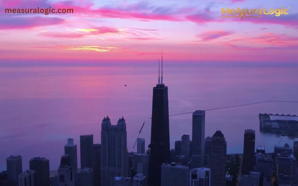 The dark silhouette of the Willis Tower and surrounding skyscrapers against a dramatic purple and pink sunset over the lake.