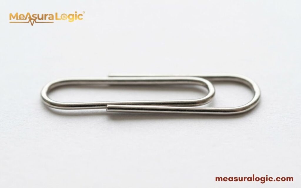 A single silver 2 inches metal paperclip. Lying horizontally on a white background.