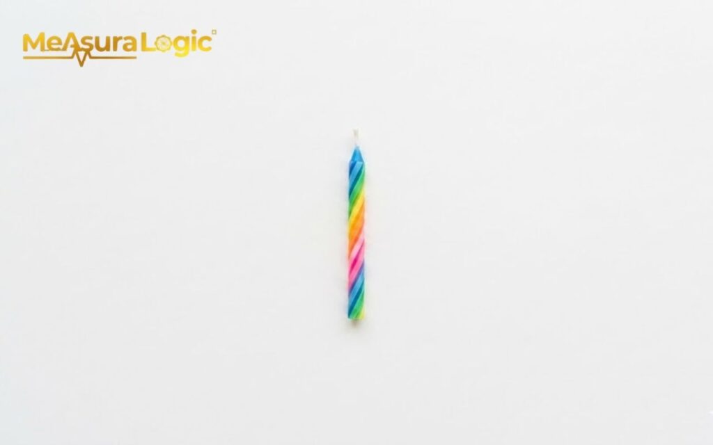 A single, unlit rainbow spiral birthday candle. Centered vertically against a plain white background.