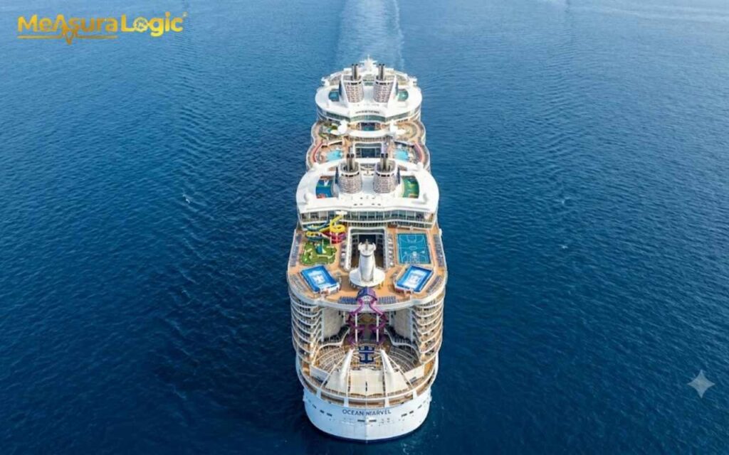 Top-down view of the large white cruise ship Ocean Marvel. Cruising across calm blue ocean with visible pool decks and water slides.