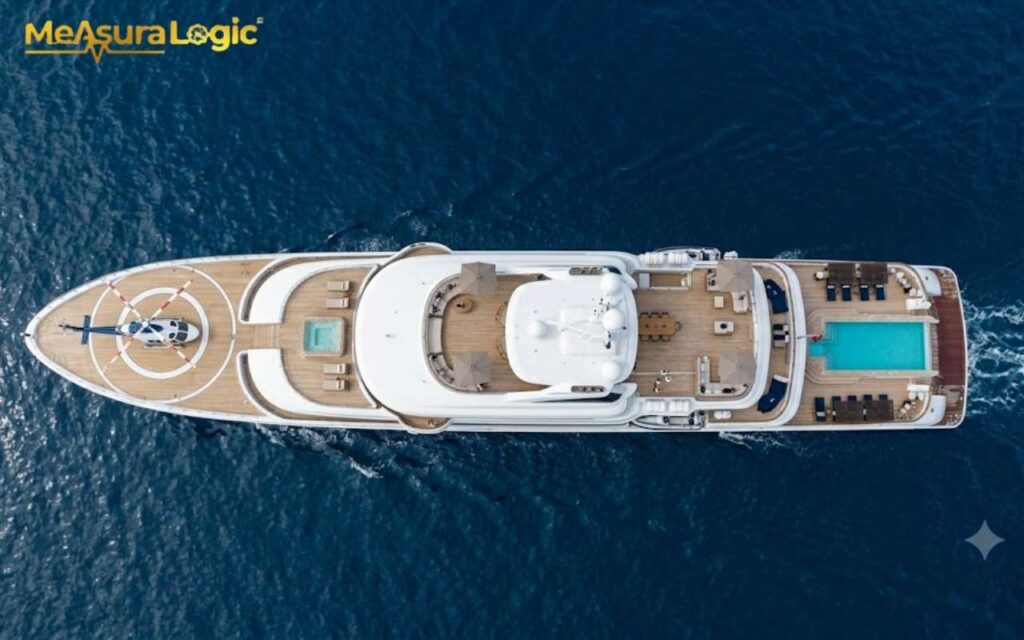 An aerial view of a luxury 300 feet long superyacht underway on blue water. Featuring a helipad with a helicopter, multiple pools, and extensive sun decks.